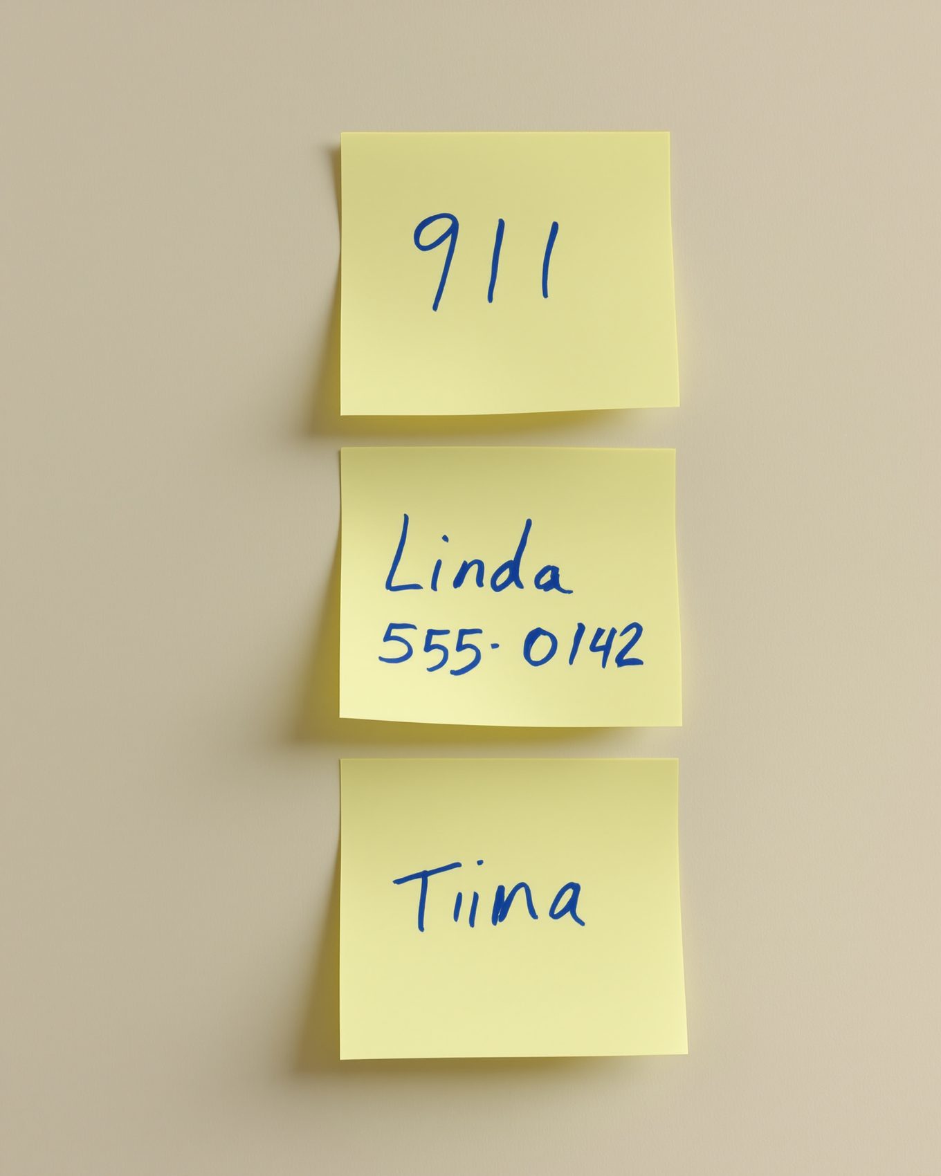 Three Post-it notes by a phone: 911, Zara 555-0142, and Tiina.
